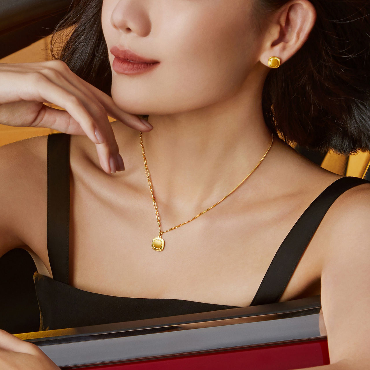 Wearing a black dress with a simple retro square gold necklace and earrings, radiating modern elegance.