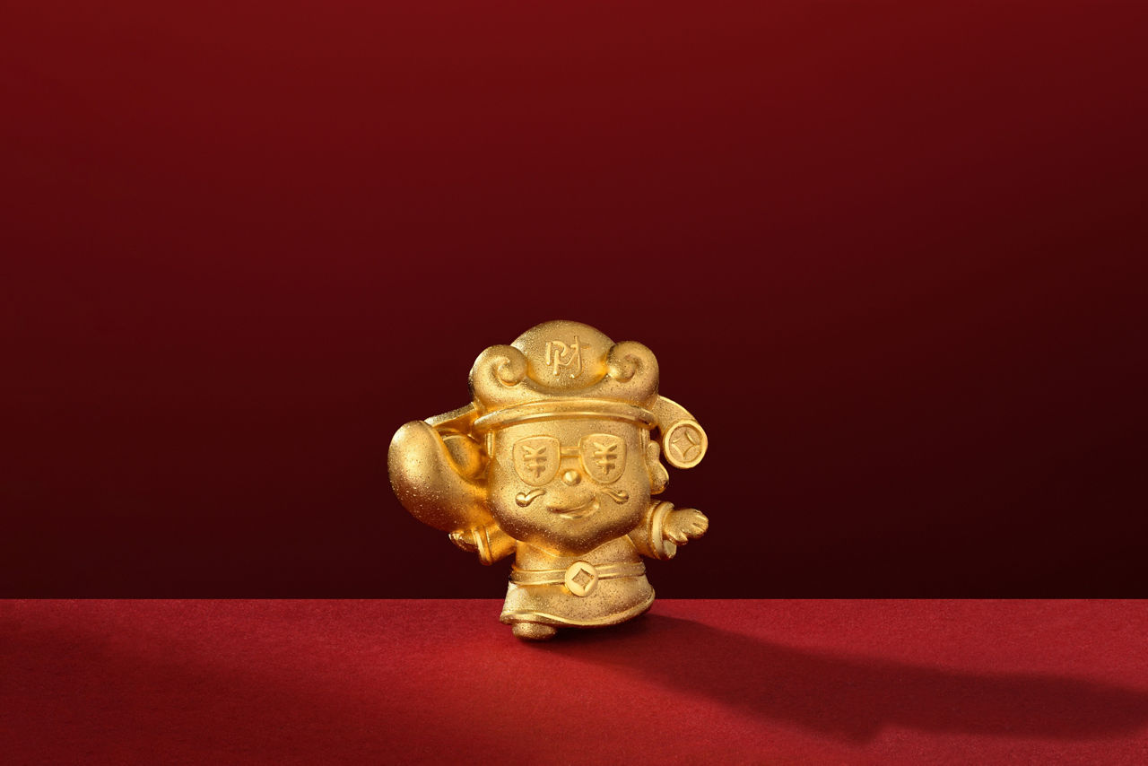 A golden ornament of the God of Wealth holding up a gold ingot, featuring exquisite craftsmanship.